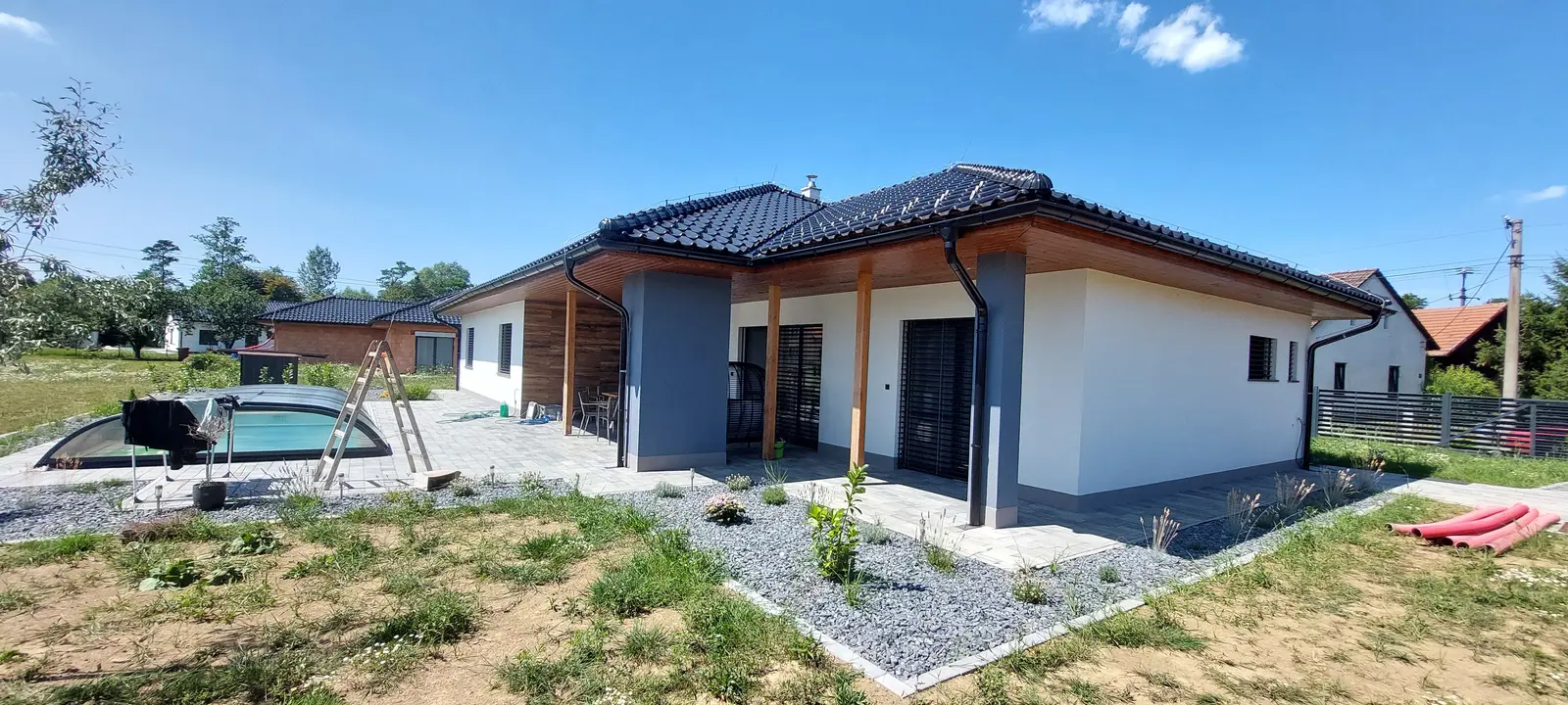 Bungalov s tmavou krytinou, okapovými žlaby a svody